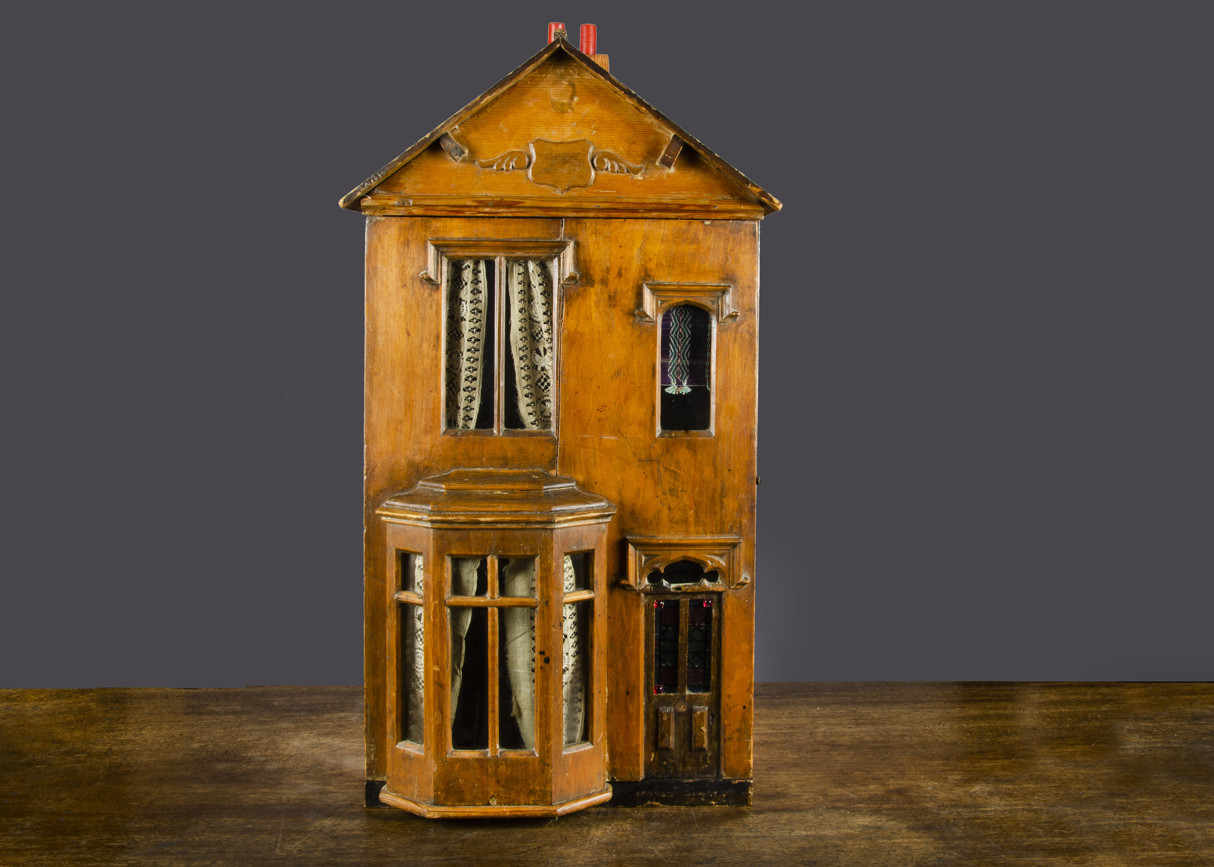 A small late 19th Century English wooden dolls’ house, pine construction with bay window, dummy