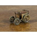 A gilt brass horseless carriage automobile tape measure, with red-painted tinplate upholstered seat,