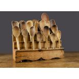 A 19th Century pine spoon rack, with three tiers and nineteen assorted wooden spoons and a fork —