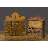 Two wooden spice cabinets, one with large salt container with wooden shovel and four drawers