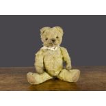 An early British teddy bear, with blonde mohair, orange and black glass eyes, pronounced muzzle,