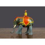 A German clockwork lithographed tinplate elephant and rider 1930s, grey with red and yellow coat/