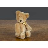 A small Schuco 1950s yes/no teddy bear, with beige mohair, brown and black glass eyes, black