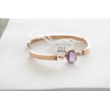 A Russian gold, amethyst and paste set bangle, the oval cut amethyst in claw setting flanked by