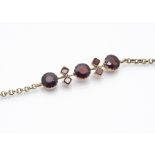 A 9ct gold garnet bracelet, the central garnet panel with three mixed circular cuts, between a