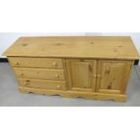 A contemporary pine cabinet, three long drawers and two panelled cupboard doors to opposite side,