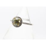 A certified fancy coloured diamond cluster ring, the claw set yellow diamond surrounded by a bezel