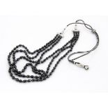 A contemporary black spinel three strand necklace, the tear shaped faceted beads on a black and