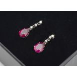 A pair of platinum and diamond ruby drop earrings, the pear shaped rubies on fine diamond set chain,