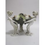 An Art Nouveau dish, modelled as three women holding a wreath of leaves and fruit, height 26cm a/f