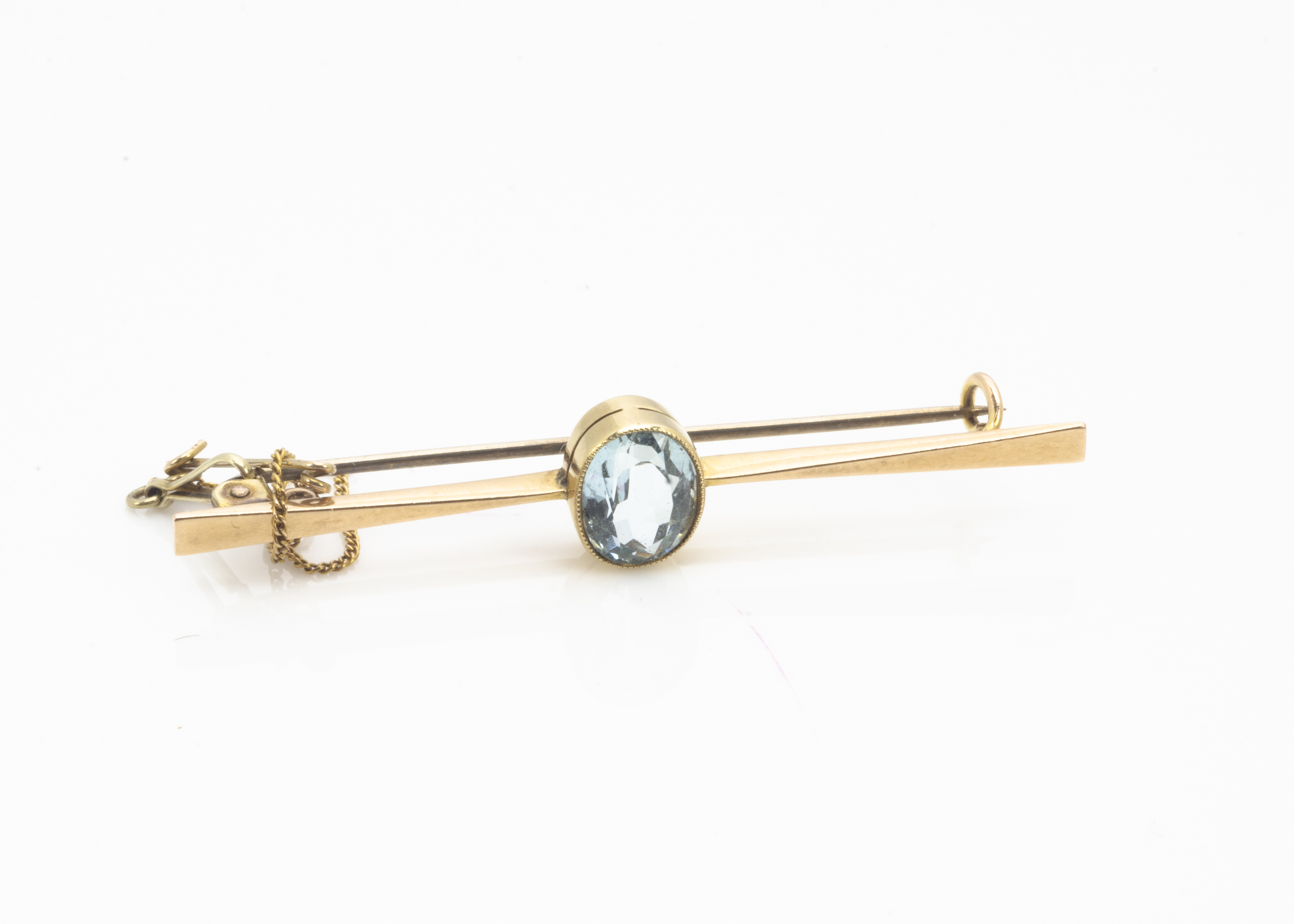 An aquamarine gold bar brooch, the mixed cut within a collet setting on a tapered bar with pin and