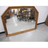 A contemporary over mantle mirror with shaped pine surround, 134cm x 106cm