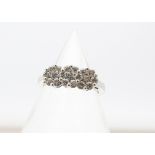 An 18ct white gold diamond triple cluster dress ring, the brilliant cuts in claw setting, with