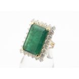 A contemporary emerald and diamond yellow metal dress ring, the central emerald cut claw set,