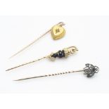 Three stick pins including a diamond set bug, a heart with gypsy set diamond and figure with a