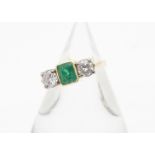 An 18ct gold three stone diamond and emerald dress ring, centred with emerald cut and claw set