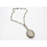 A George V silver oval hinged locket, with engraved leaf design, on an oval linked watch chain,