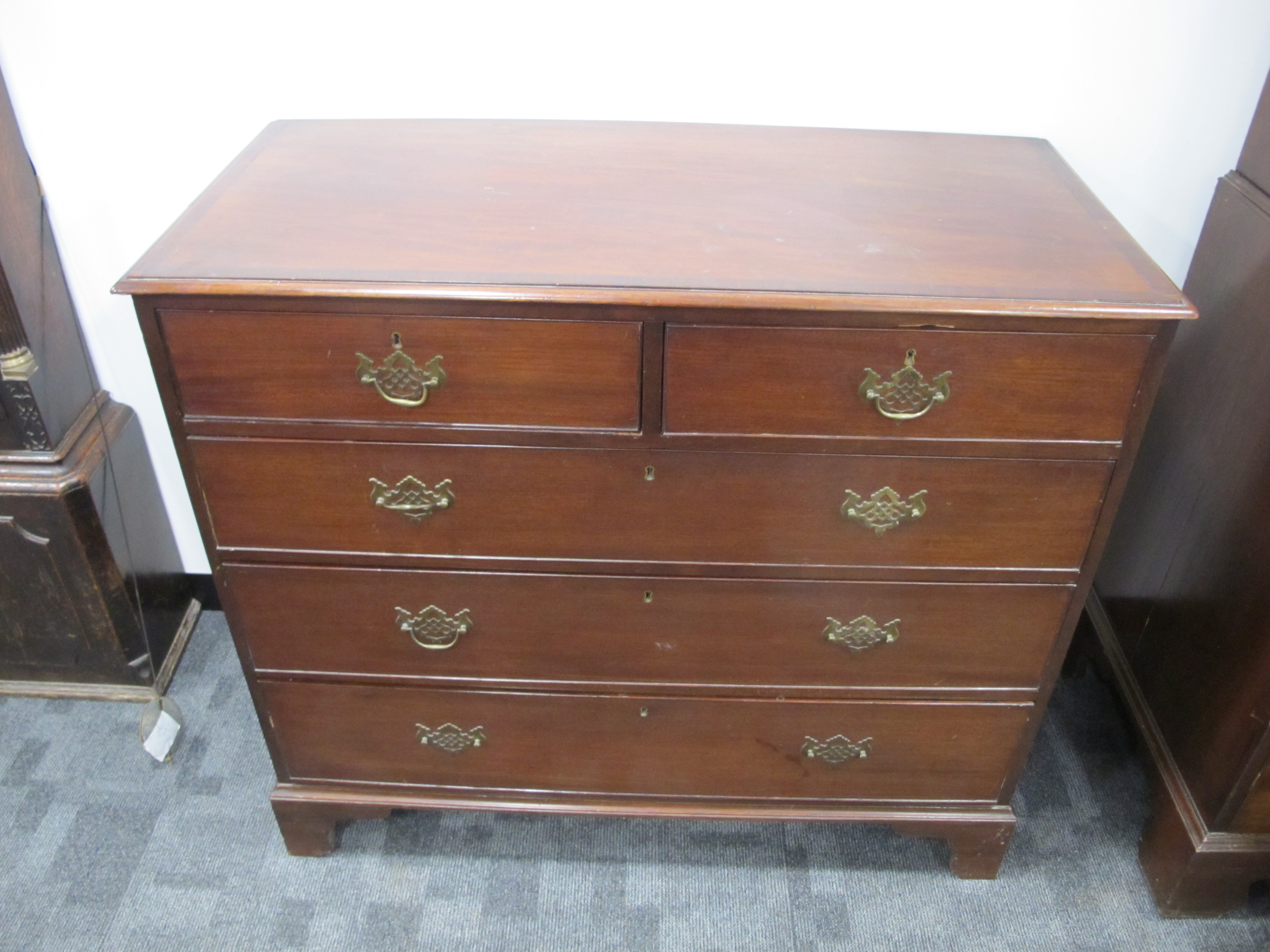 A Georgian mahogany chest of two short and three long graduate drawers, cross banded top, raised