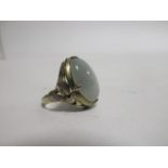 A Chinese jade dress ring, the oval cabochon jade set within four claw silver gilt leaf decorated