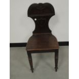 A William IV mahogany hall chair, shaped seat, with shield back, raised on turned front supports,