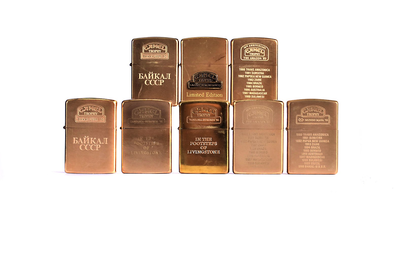 A collection of yellow-metal Camel Trophy Zippo Lighters, to include two 1989 Brazil, first of the
