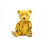 A 1950s Chiltern Hugmee teddy bear, with golden mohair, orange and black plastic eyes, black