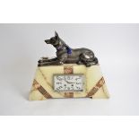 A large Art Deco marble and onyx mantel clock, surmounted with an Alsatian, 38cm high x 45cm wide