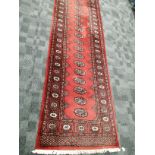 A Middle Eastern Wool runner, with floral and geometric motifs upon a pink ground, tassels to either