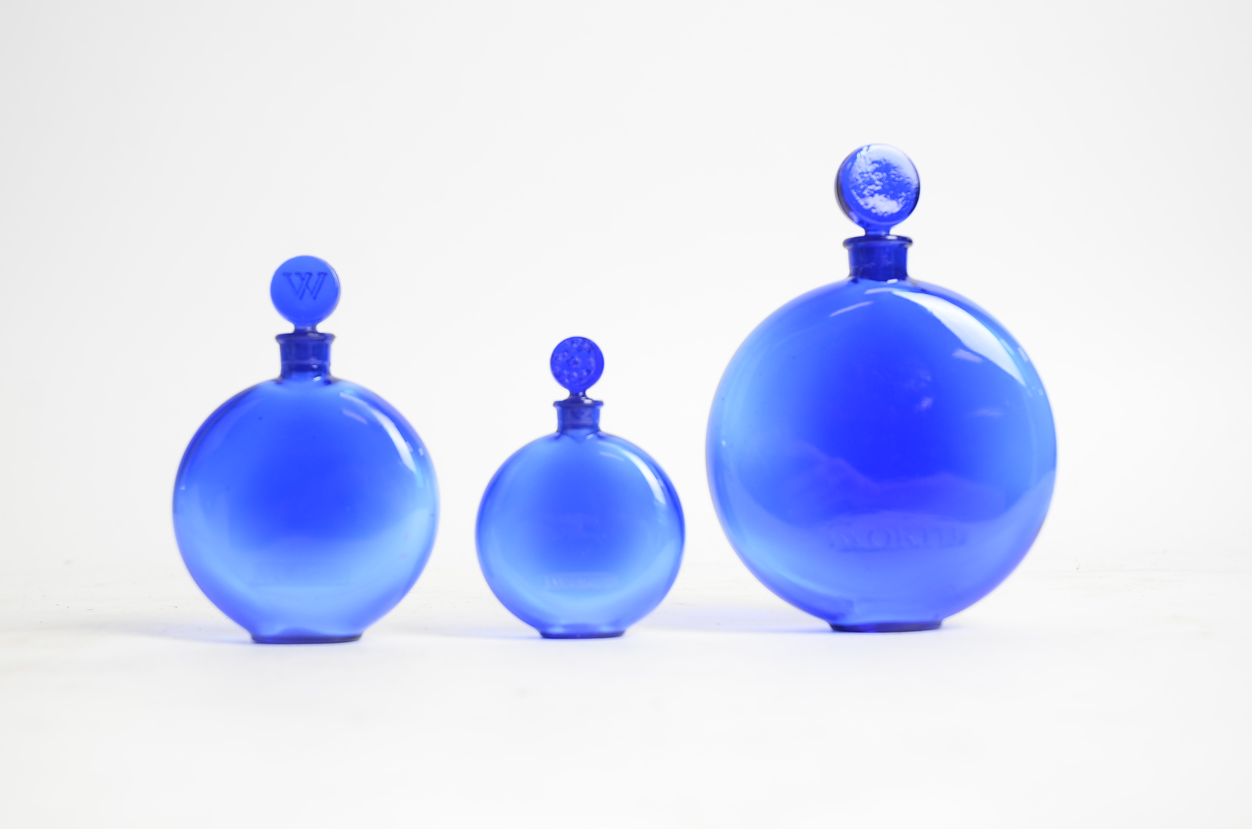 René Lalique (French, 1860-1945) a graduated set of three blue glass circular Worth perfume bottles, - Image 2 of 2