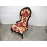 A Victorian walnut framed spoon back nursing chair, floral decorated carved frame, raised on front
