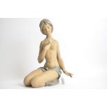 A Lladro bisque figure of a kneeling semi nude girl holding a rose, of substantial proportions,