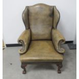 A Georgian style wing armchair , mushroom coloured leather upholstery with brass studding, raised on