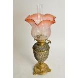 A Doulton oil lamp with cranberry glass shade, the Doulton stoneware body raised on three footed