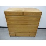 A Cotswold School style chest of drawers, oak with panelled sides and tops, mahogany drawer side,