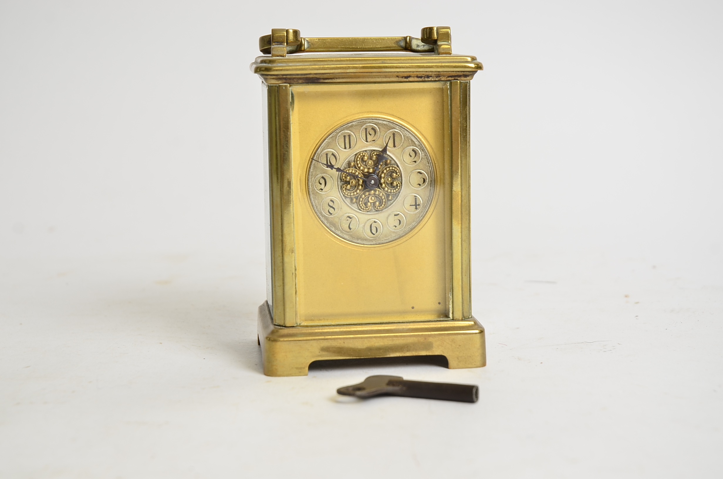 A brass carriage timepiece, the dial with Arabic numerals and decorative central panel, height