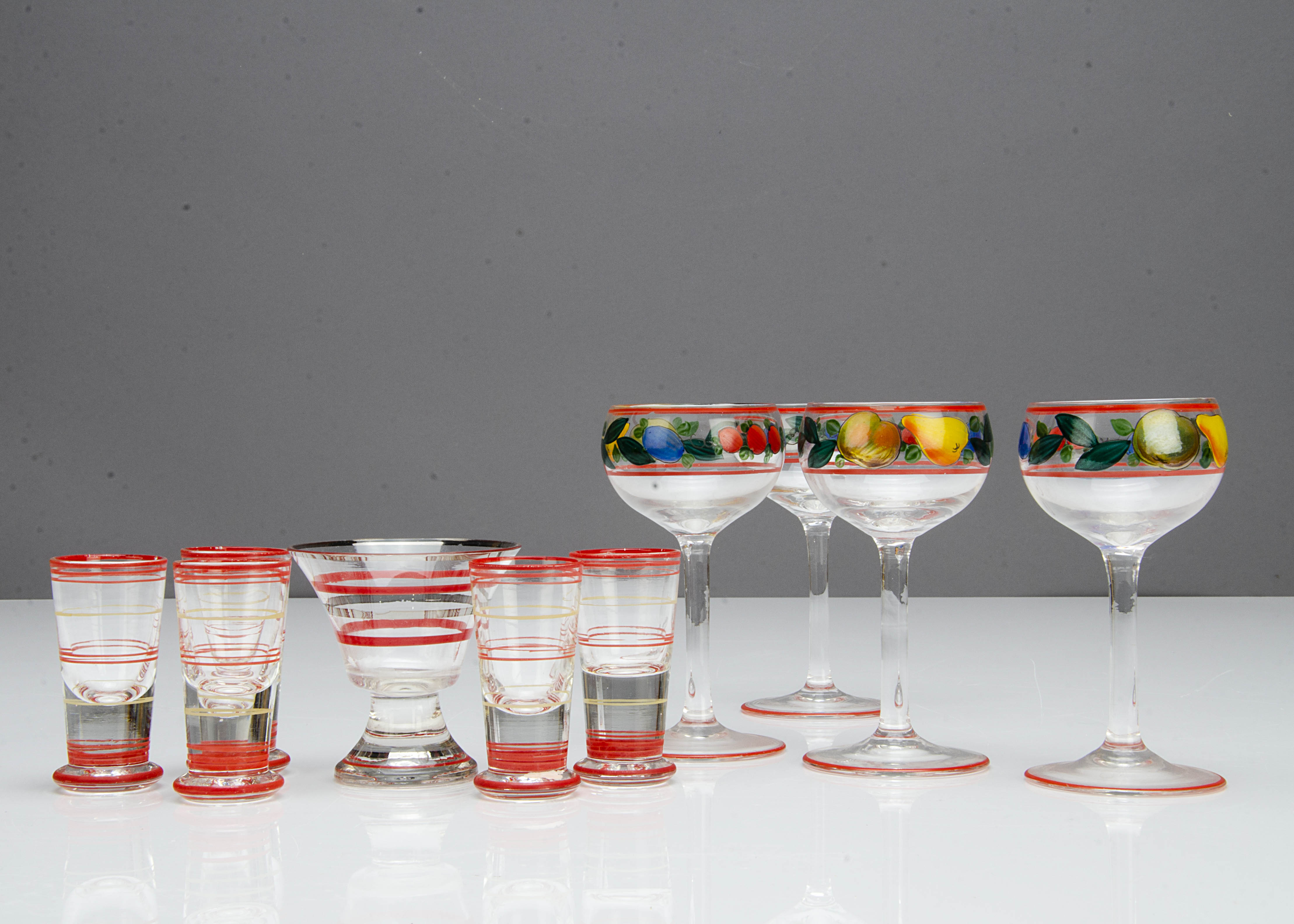 A set of four painted glass liquor glasses, decorated with fruit with red banding, 12cm, a banded