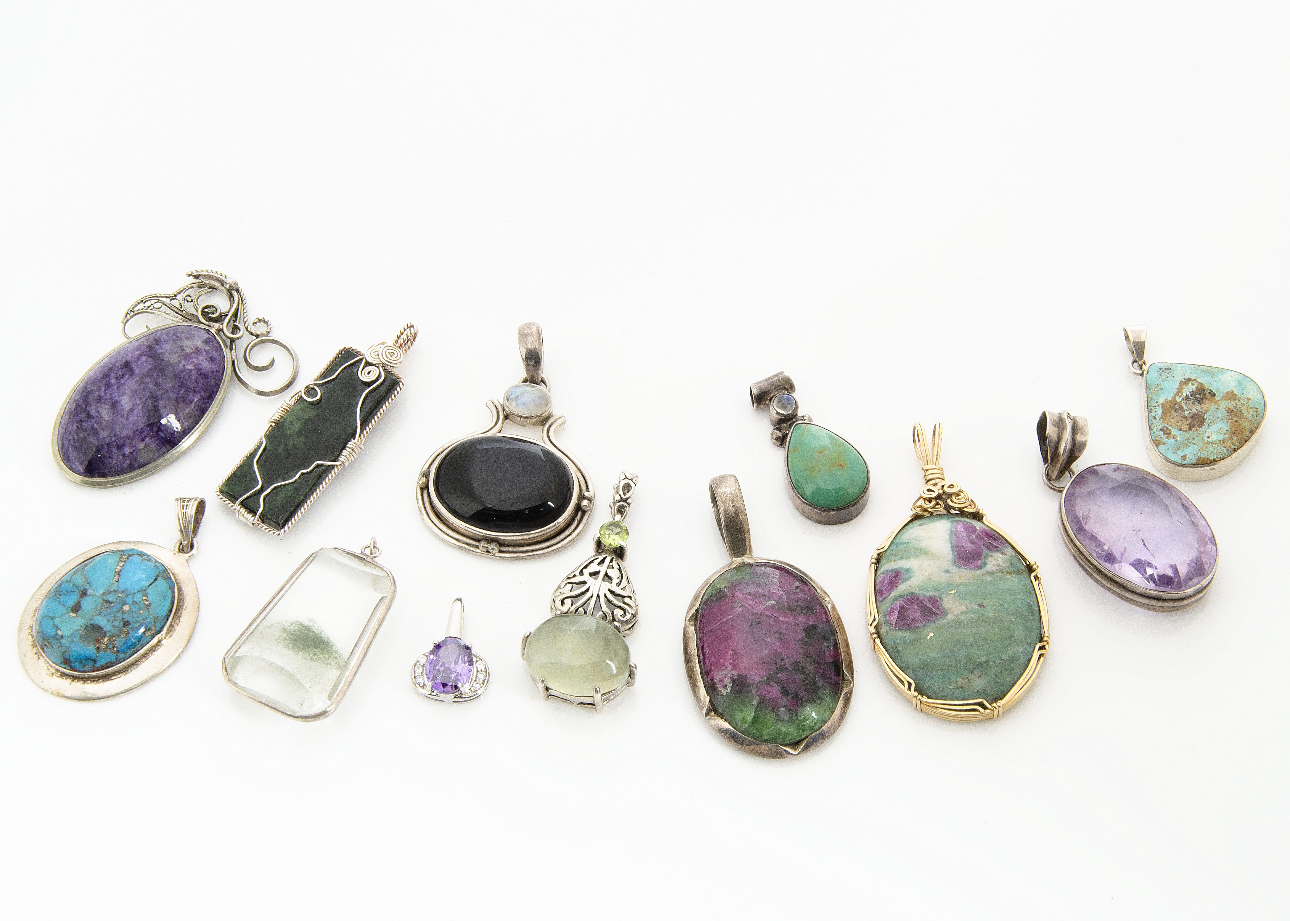 A collection of hardstone pendants, including three turquoise set in silver, an amethyst matrix in