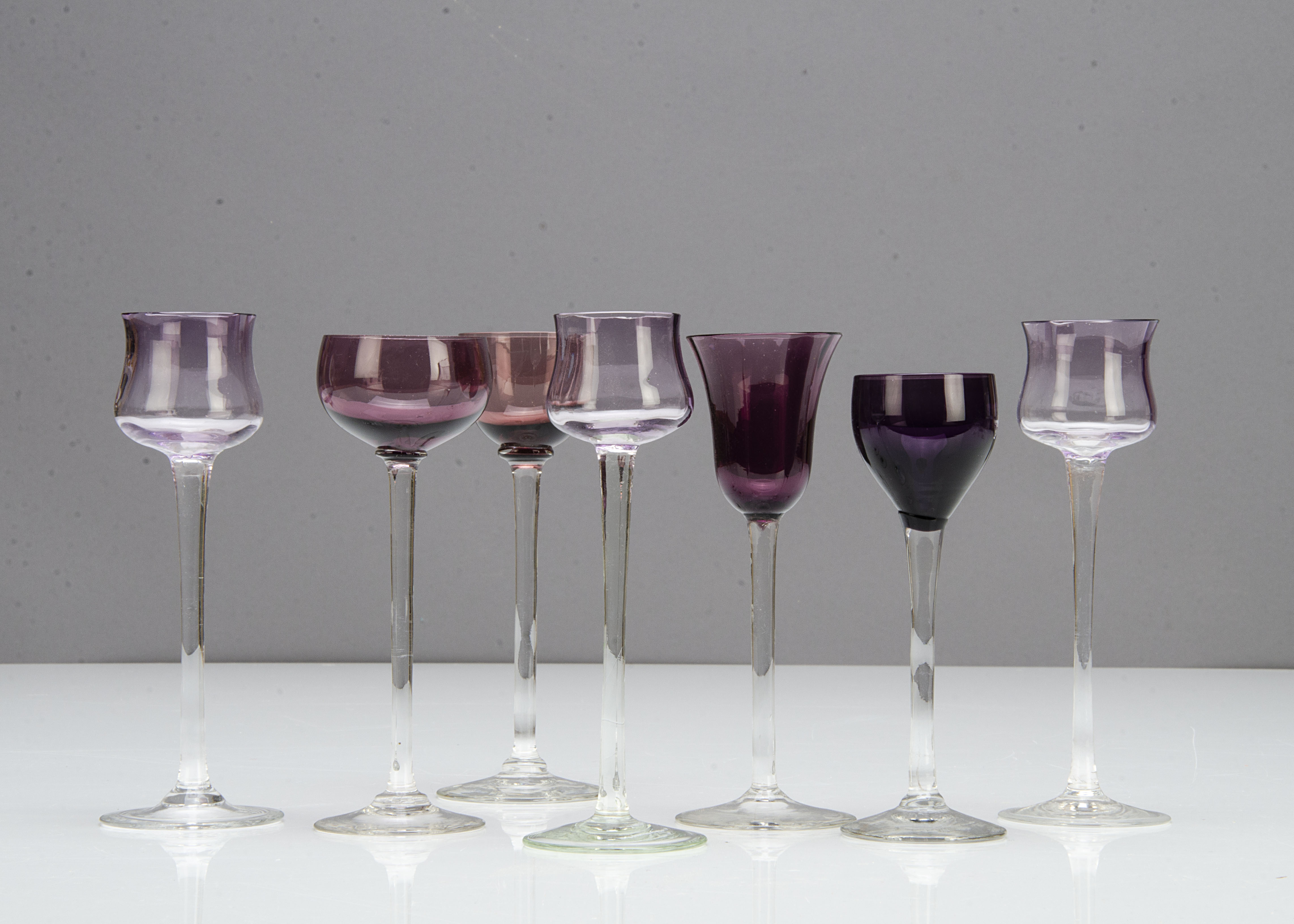 A set of three German Art Nouveau tulip shaped amethyst coloured liquor glasses, with amethyst bowls