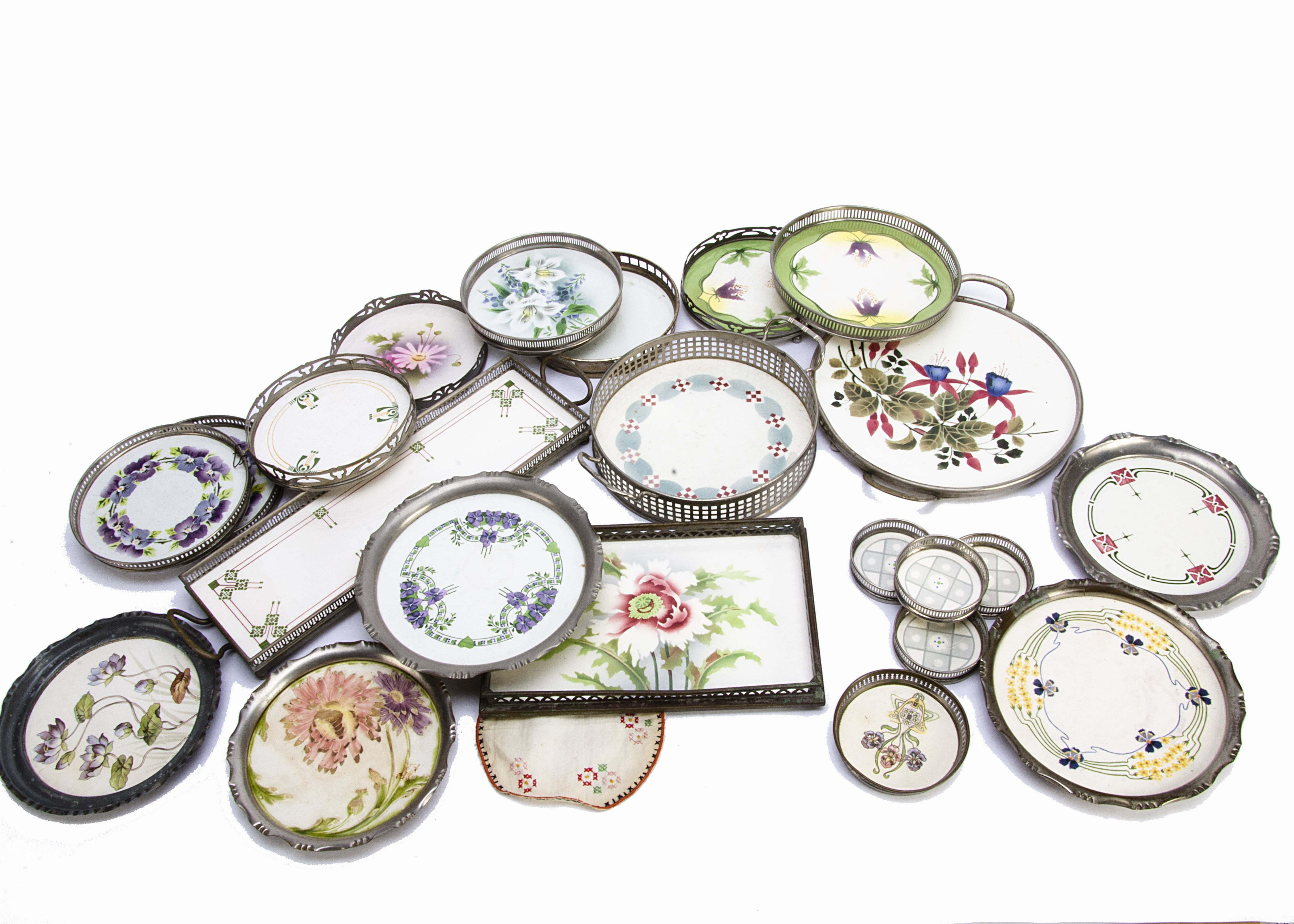 A collection of early 20th Century pottery and base metal Art Nouveau decorated coasters, teapot