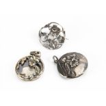 Three white metal floral Art Nouveau and Art Nouveau style pendants and brooches, comprising a