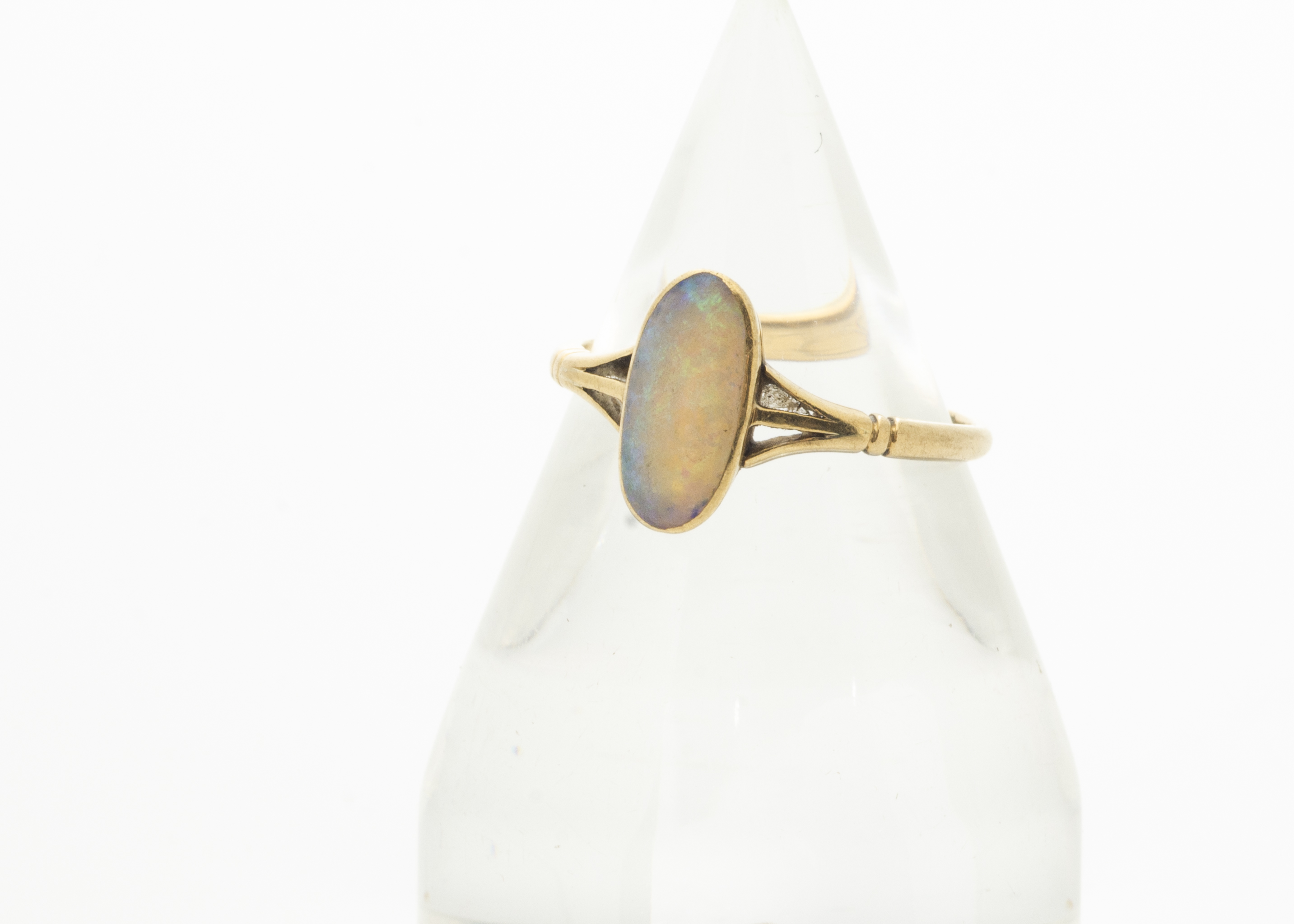 An 18ct gold opal dress ring, the elongated precious oval opal in rubbed over setting with pierced