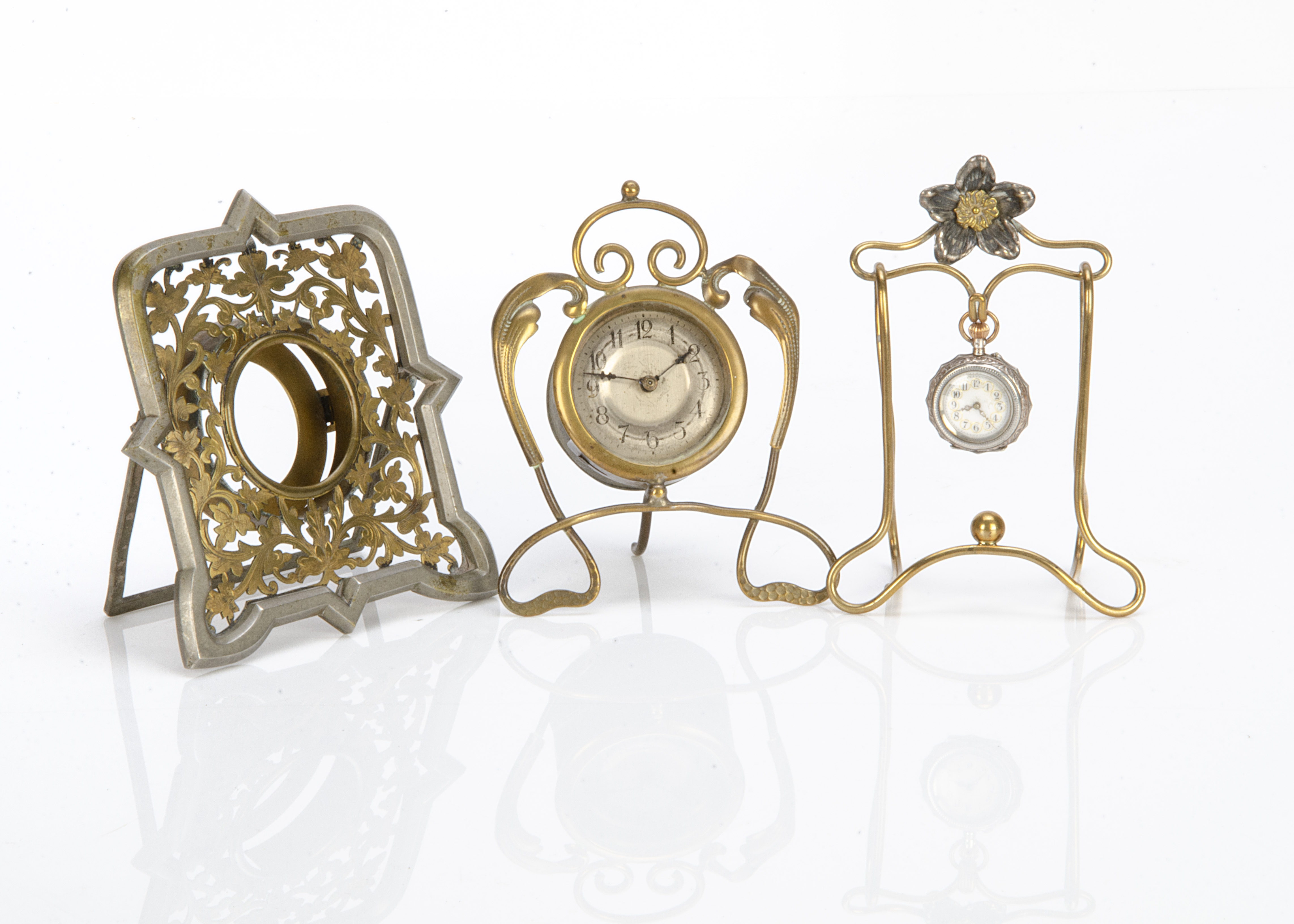 Three early 20th Century pocket watches and stands, one in the Edwardian Art Nouveau style with drum
