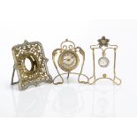 Three early 20th Century pocket watches and stands, one in the Edwardian Art Nouveau style with drum