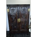 A Chinese hardwood 20th Century linen cabinet, with pair of panelled doors carved with bats