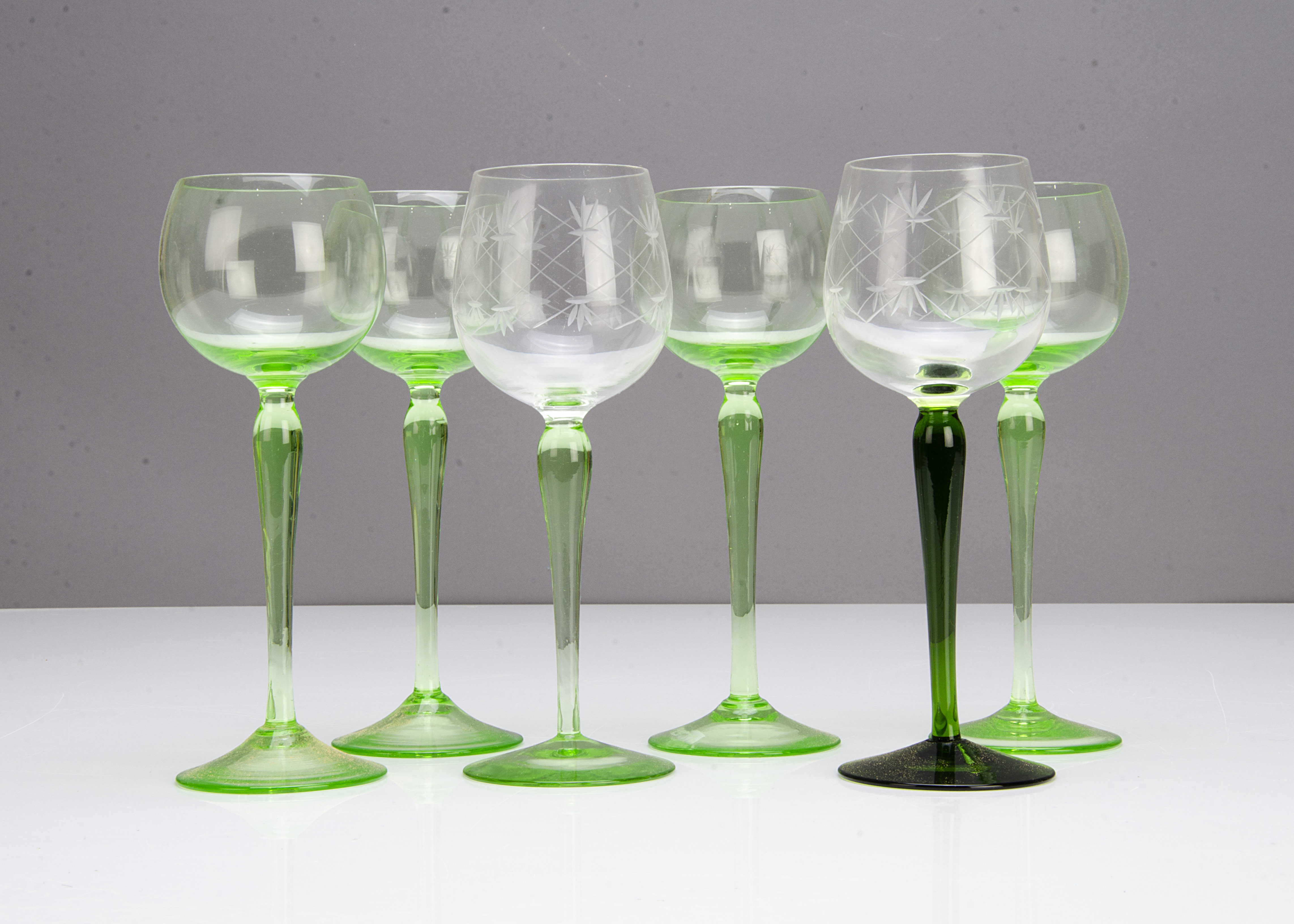 A set of four continental Art Nouveau green wine glasses, the circular bowls with waisted and