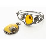 A contemporary Baltic amber bangle, the oval cabochon in pierced white metal leaf setting marked