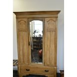 An Art Nouveau oak veneered and inlaid wardrobe, with middle bevelled glass arched door flanked by