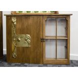 A contemporary oak cabinet, opening to reveal shelved interior decorated with Art Nouveau brass door