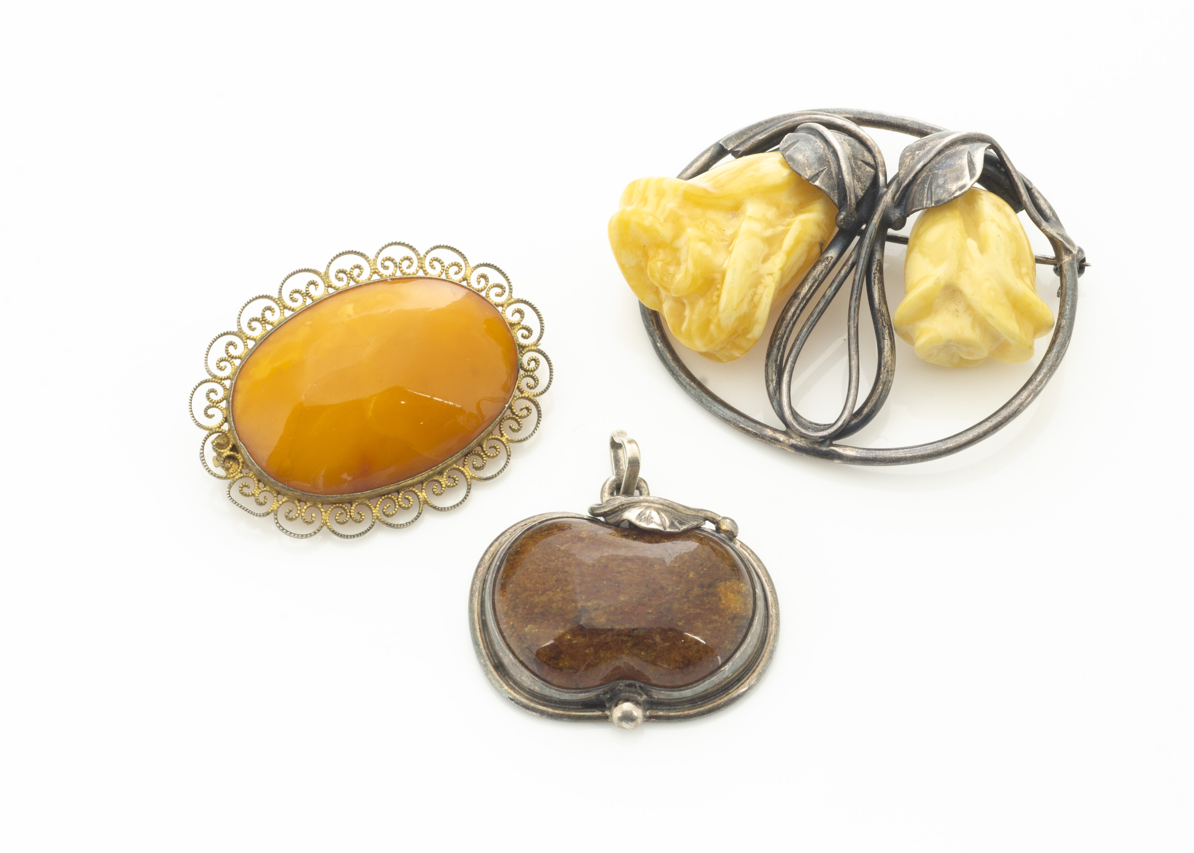 A silver and amber floral brooch, the carved amber flower heads within a pierced silver leaf