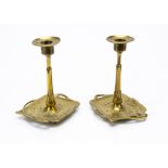 A pair of German Jugendstil brass candlesticks, the square trays decorated with stylised flowers,